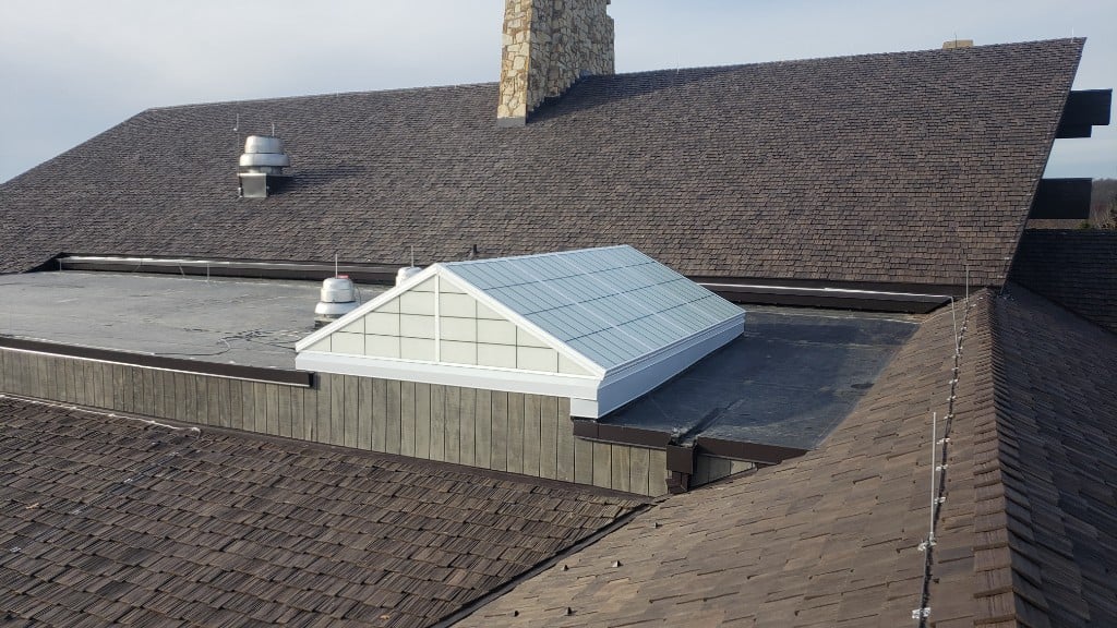 Complex roof with shake shingles, flat membrane section, and large skylight
